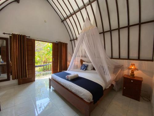 a bedroom with a bed with a mosquito net at Mustika Ocean Lodge in Gili Air