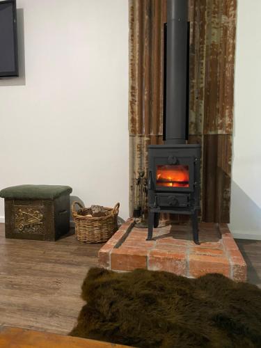 a stove in a living room with a fireplace at Holly House Garden Studio in Moyhu