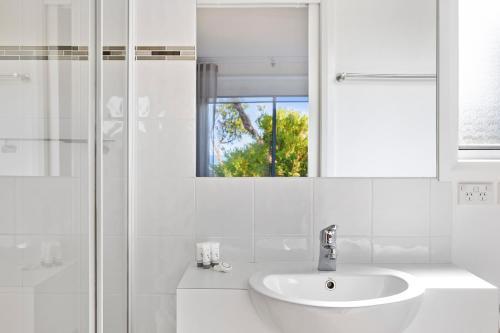 a white bathroom with a sink and a mirror at Ingenia Holidays Cape Paterson in Cape Paterson