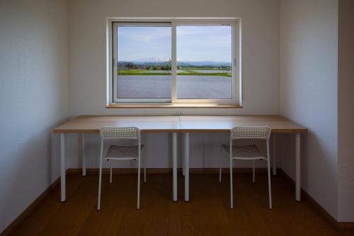 a table and two chairs in a room with a window at Yadoya YADOKARI 2nd in Pippu