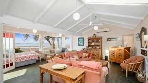 a living room with a couch and a table at Beachside Bliss - Waiwera Beachfront Holiday Home in Orewa