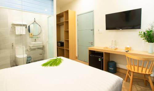 Dormitorio con cama, escritorio y TV en Vy's House Phanthiet Hotel, en Ấp Tân An (1)