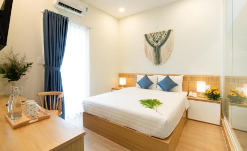 a bedroom with a bed and a table and a desk at Vy's House Phanthiet Hotel in Ấp Tân An (1)