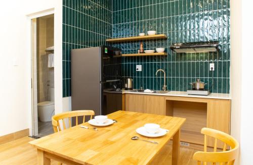 a kitchen with a wooden table and a green wall at Vy's House Phanthiet Hotel in Ấp Tân An (1)
