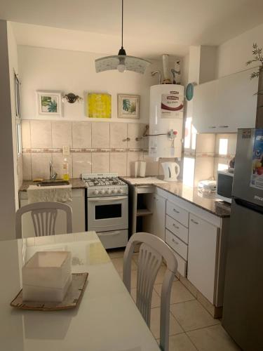 una cocina con electrodomésticos blancos, mesa y sillas en SUNSET en General Roca