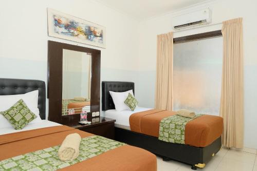 a hotel room with two beds and a mirror at The Kirana Purnama Semarang in Semarang