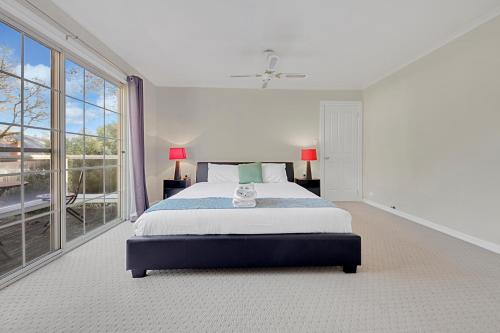 a white bedroom with a bed and a large window at 406 Back Porepunkah Road, Bright in Bright