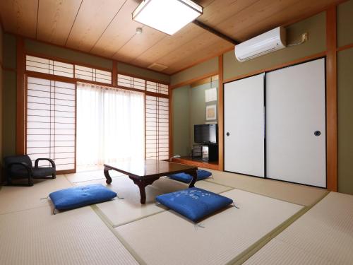 a living room with a table and two blue cushions at Naitouya in Minamichita