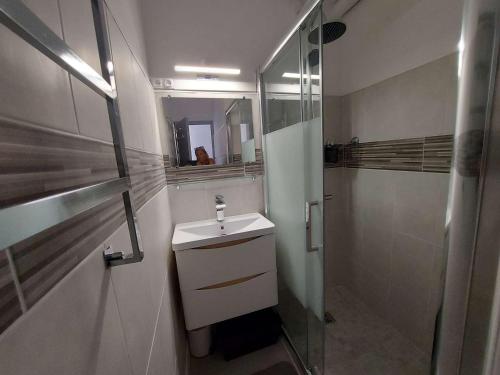une salle de bain blanche avec un lavabo et une douche dans l'établissement Grau d'Agde: Appt 2P rénové à 20m de la plage - FR-1-423-282, au Grau-dʼAgde