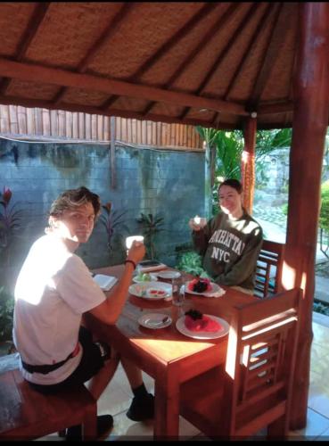 two people sitting at a wooden table with food at Maha Nusa Menjangan in Banyuwedang