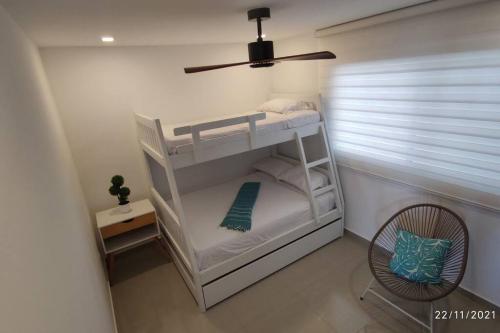 a small bedroom with a bunk bed with a fan at Departamento Playero Fontaine Bleau Frente al Mar Tonsupa in Tonsupa