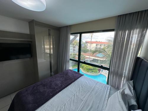 a bedroom with a bed and a large window at Marulhos Resort Beach - 2 quartos & 1 quarto in Porto De Galinhas