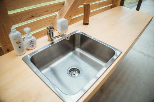 a stainless steel sink in a kitchen with two bottles of soap at Solabase in Kazo