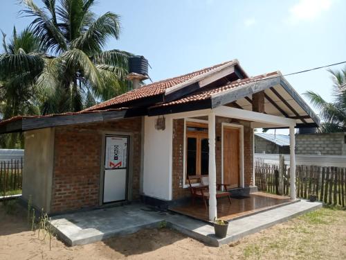 a small house with a porch on the beach at Aiden Homestay in Pasikuda