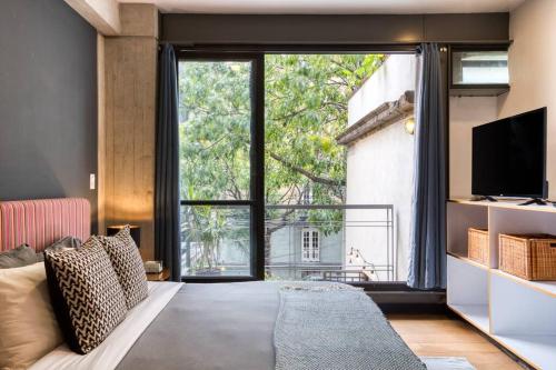 a living room with a couch and a large window at Unique Roma Apartments S51 By MrW in Mexico City