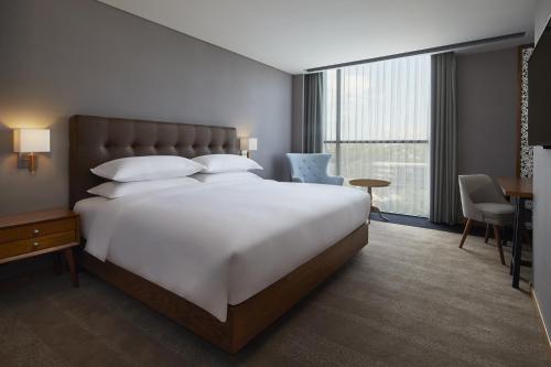 a hotel room with a large white bed and a desk at Four Points by Sheraton Balikpapan in Balikpapan