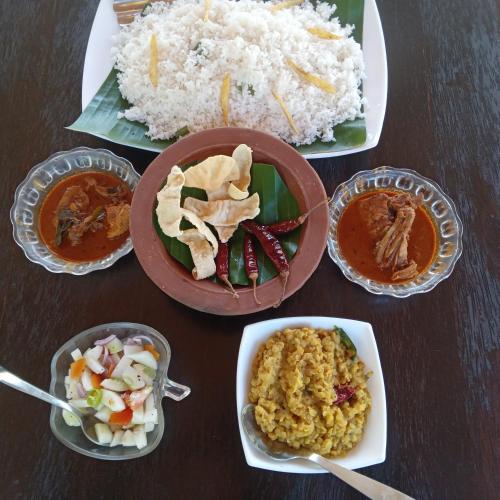 a table with plates of food and bowls of rice at Aiden Homestay in Pasikuda