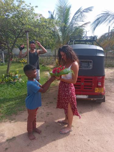 a woman holding a boy holding a bunch of flowers at Aiden Homestay in Pasikuda