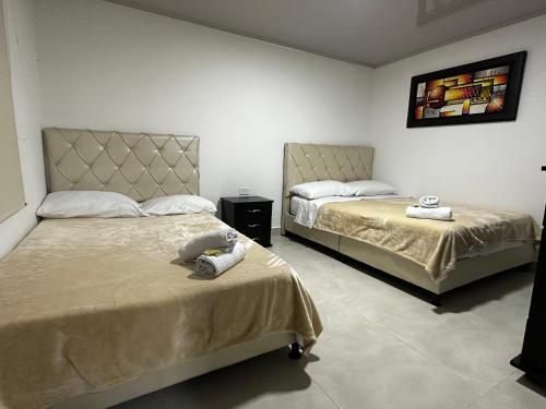 1 dormitorio con 2 camas y TV en la pared en Finca Hotel Villa Celeste, en Quimbaya