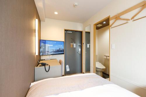 a hotel room with a bed and a tv at HOTEL Third Place Hakata in Fukuoka