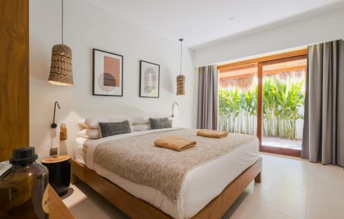 a bedroom with a large bed and a balcony at Amber Lombok Beach Resort in Selong Belanak