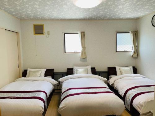 a room with four beds in it with windows at 山中湖リゾートハウス in Yamanakako