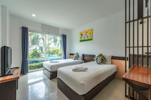 a bedroom with two beds and a tv and a window at The One Cozy Vacation Residence SHA Hotel in Chalong 