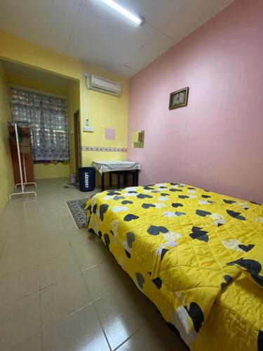 a bedroom with a bed with a yellow comforter at EQ Malay Modest Homestay Port Dickson in Port Dickson