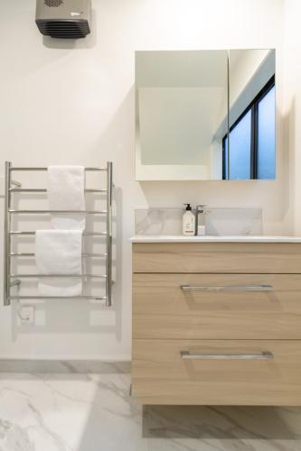 a bathroom with a sink and a mirror and towels at 3 Bedroom 2 Bathroom Hagley Parkside Perch in Christchurch