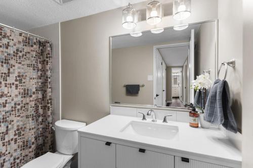 a bathroom with a sink and a toilet and a mirror at Newly Renovated 2 Bedroom Downtown Saskatoon Condo in Saskatoon