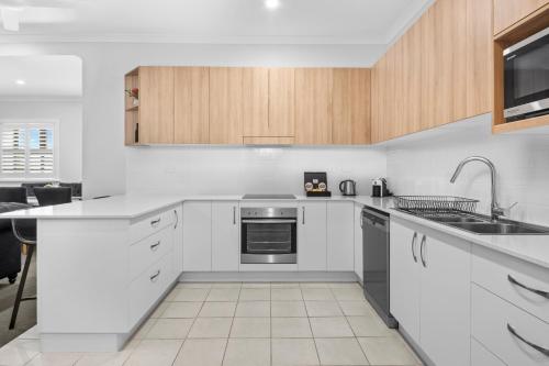 an empty kitchen with white cabinets and a sink at CocoBrew Boutique Apartments in Rockhampton