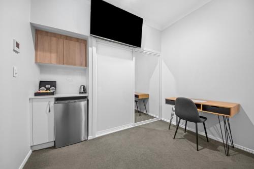 a kitchen with a table and a desk with a television at CocoBrew Boutique Apartments in Rockhampton