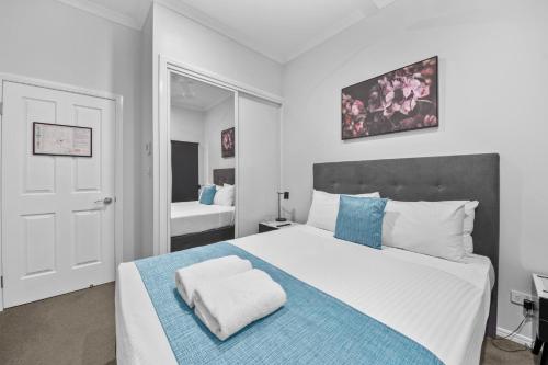 a bedroom with a large bed with blue and white pillows at CocoBrew Boutique Apartments in Rockhampton