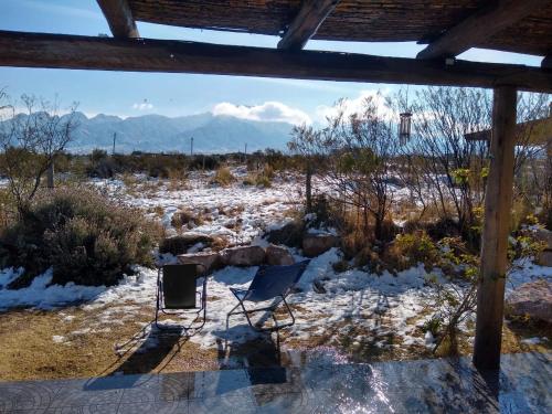 una silla sentada en la nieve con montañas en el fondo en Casa Entelequia en Las Compuertas