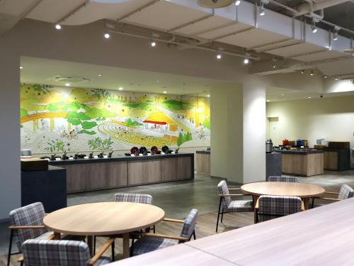 a restaurant with tables and chairs and a large mural at WeBase TAKAMATSU in Takamatsu