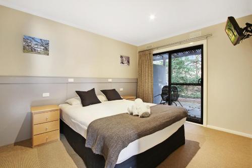 a bedroom with a large bed and a window at Grevillea Gardens Unit 8 in Bright