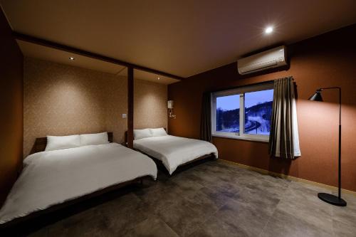 two beds in a room with a window at The Landmark in Furano