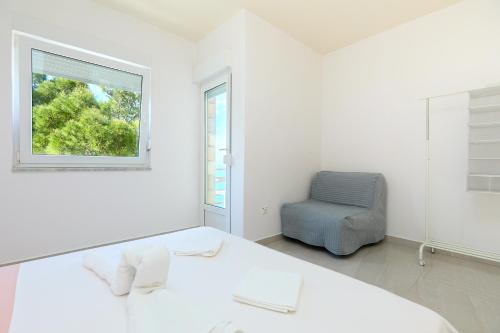 ein weißes Schlafzimmer mit einem Bett und einem Stuhl in der Unterkunft Apartmets Sutmiholjska in Babino Polje