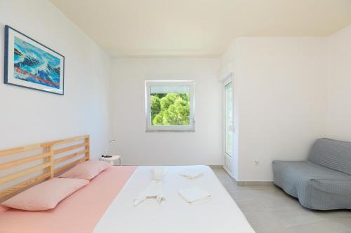 ein weißes Schlafzimmer mit einem Bett und einem blauen Sofa in der Unterkunft Apartmets Sutmiholjska in Babino Polje