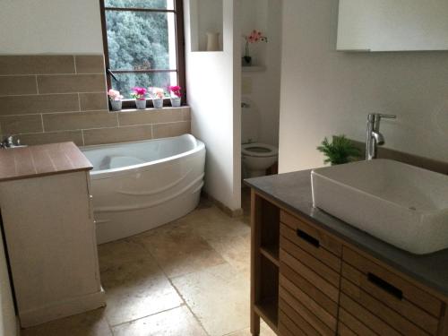 ein Badezimmer mit einer weißen Badewanne und einem Waschbecken in der Unterkunft Mas provençal dans un lieu exceptionnel in Bollène