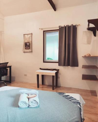 a bedroom with a bed and a window and a table at Prana Siargao Resort in General Luna