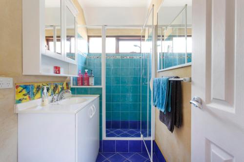 a bathroom with a sink and a shower with blue tiles at Binks Beach House - South Fremantle in South Fremantle