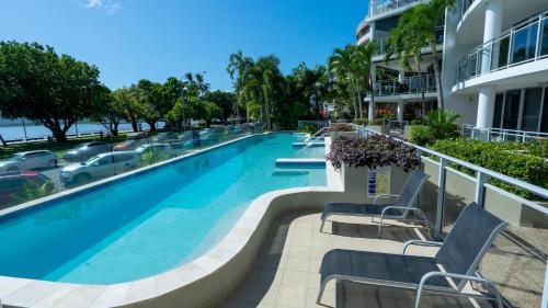 Una piscina con sillas y un edificio. en Vision Apartments, en Cairns
