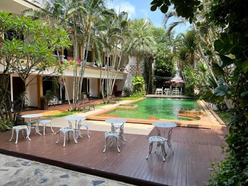 a patio with tables and chairs next to a swimming pool at Hotel La Villa Khon Kaen in Khon Kaen