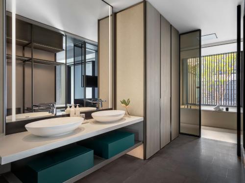 baño con 2 lavabos y espejo grande en Kimpton Bamboo Grove Suzhou, an IHG Hotel en Suzhou