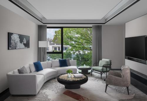 a living room with a white couch and a tv at Kimpton Bamboo Grove Suzhou, an IHG Hotel in Suzhou