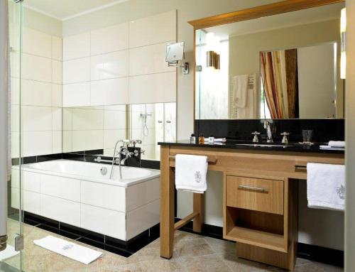 a bathroom with a tub and a large mirror at Gut Kump Gastronomie und Hotel in Hamm