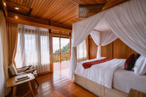 a bedroom with a canopy bed and a balcony at Munduk Menir Villas in Munduk