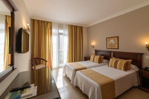 a hotel room with two beds and a television at Hotel Marte in Puerto de la Cruz