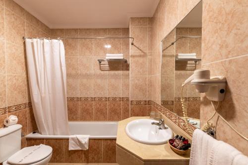 a bathroom with a sink and a toilet and a tub at Hotel Marte in Puerto de la Cruz